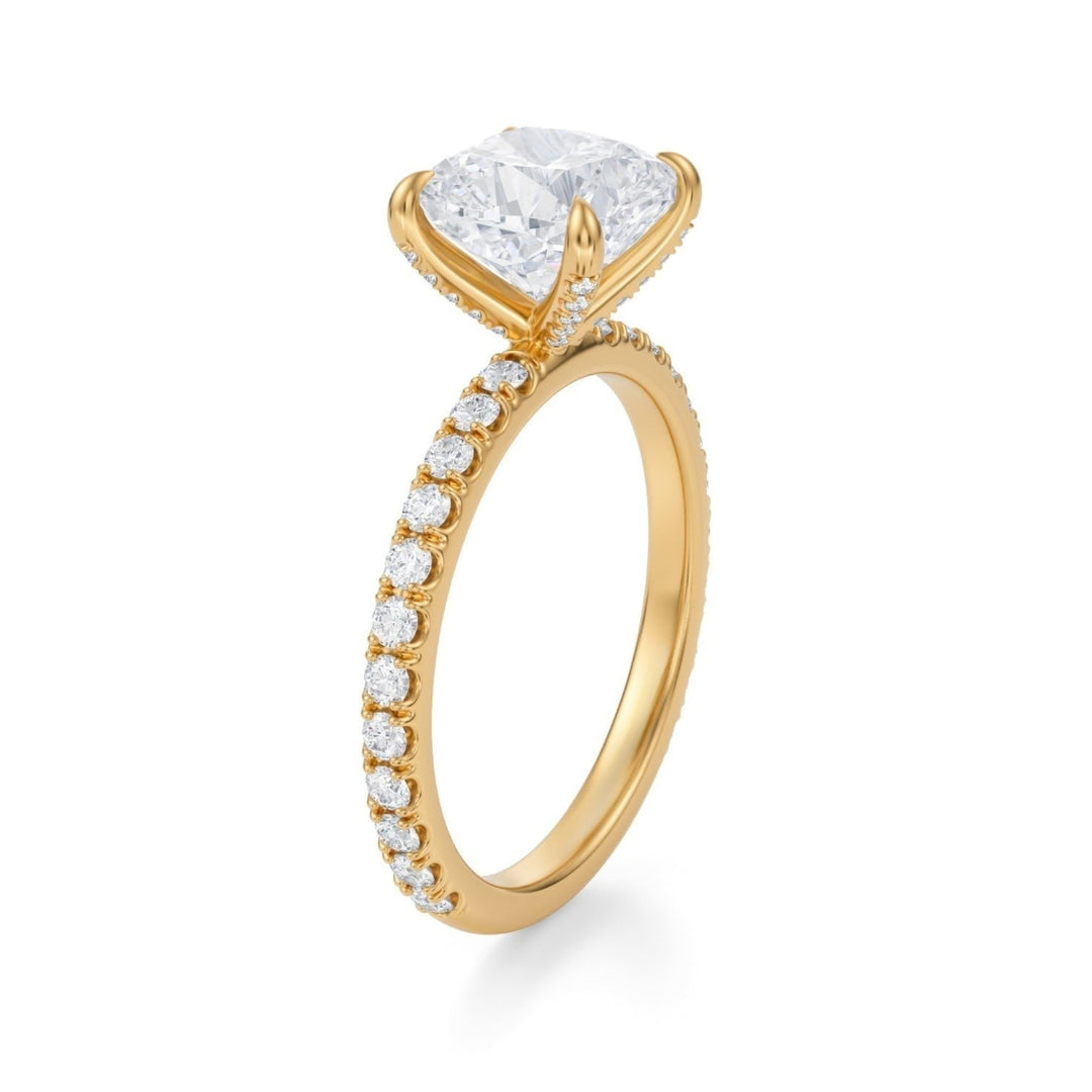 A cushion-cut diamond ring with pave-set side stones and prongs, displayed against a white background.
