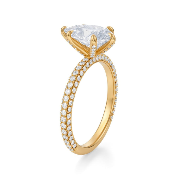 A silver ring with a pear-shaped central diamond encircled by a trio of smaller pave diamonds, set against a white background.