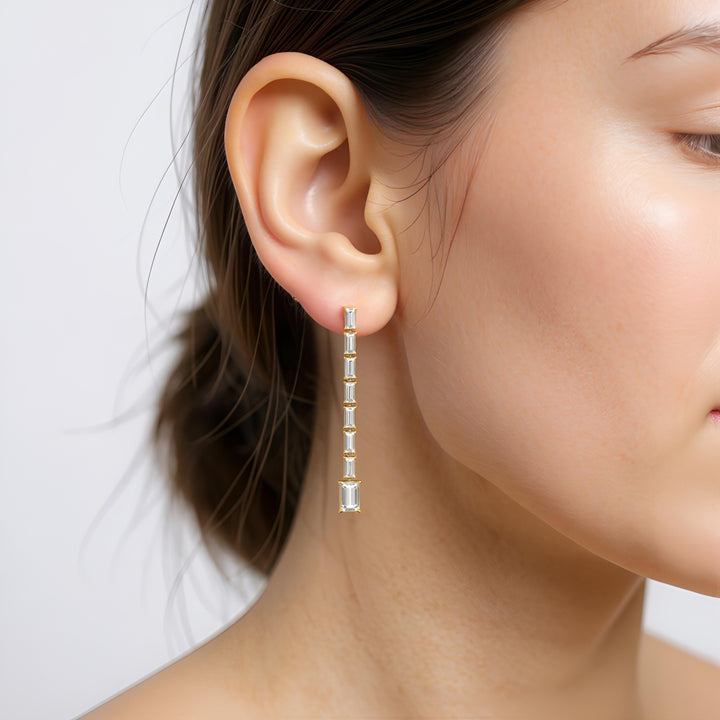 Close-up of a person wearing a diamond earring on a plain background