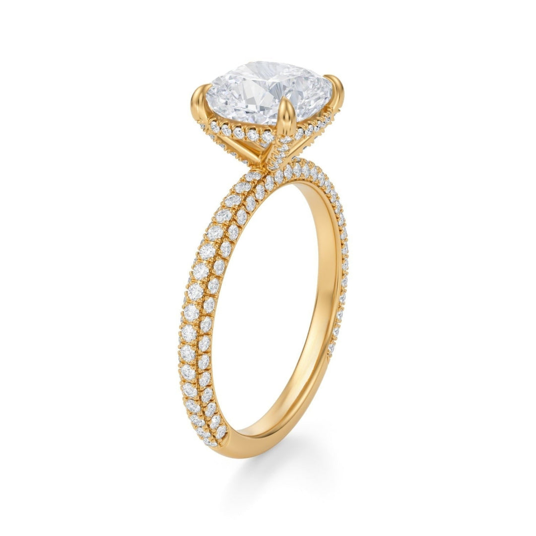 A cushion cut diamond ring with a pave band, displayed on a white background.