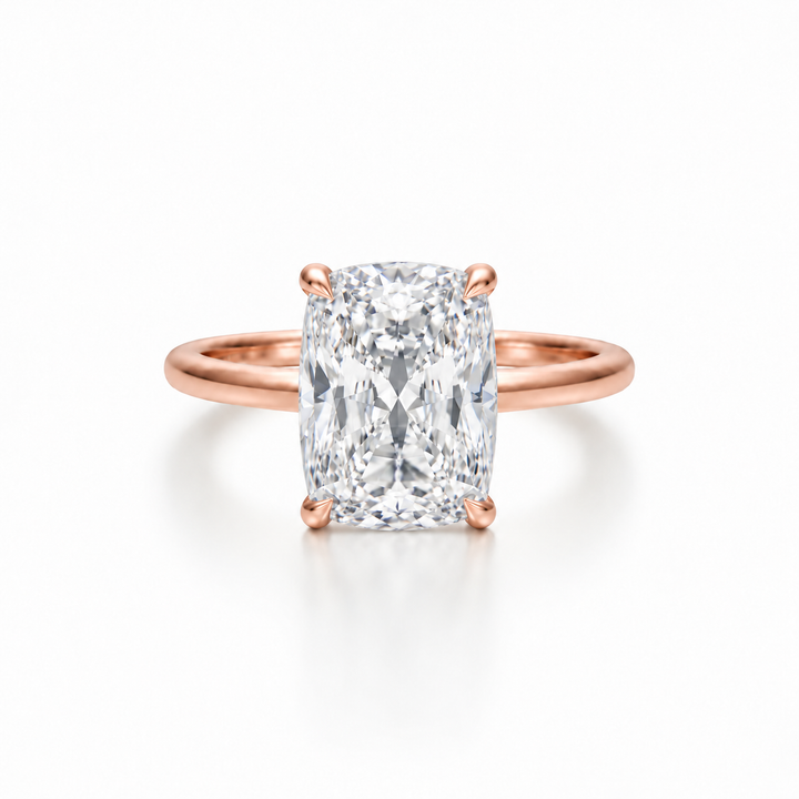 Front view of an elongated cushion diamond solitaire ring in a rose gold cathedral setting with four-prong claw detail.